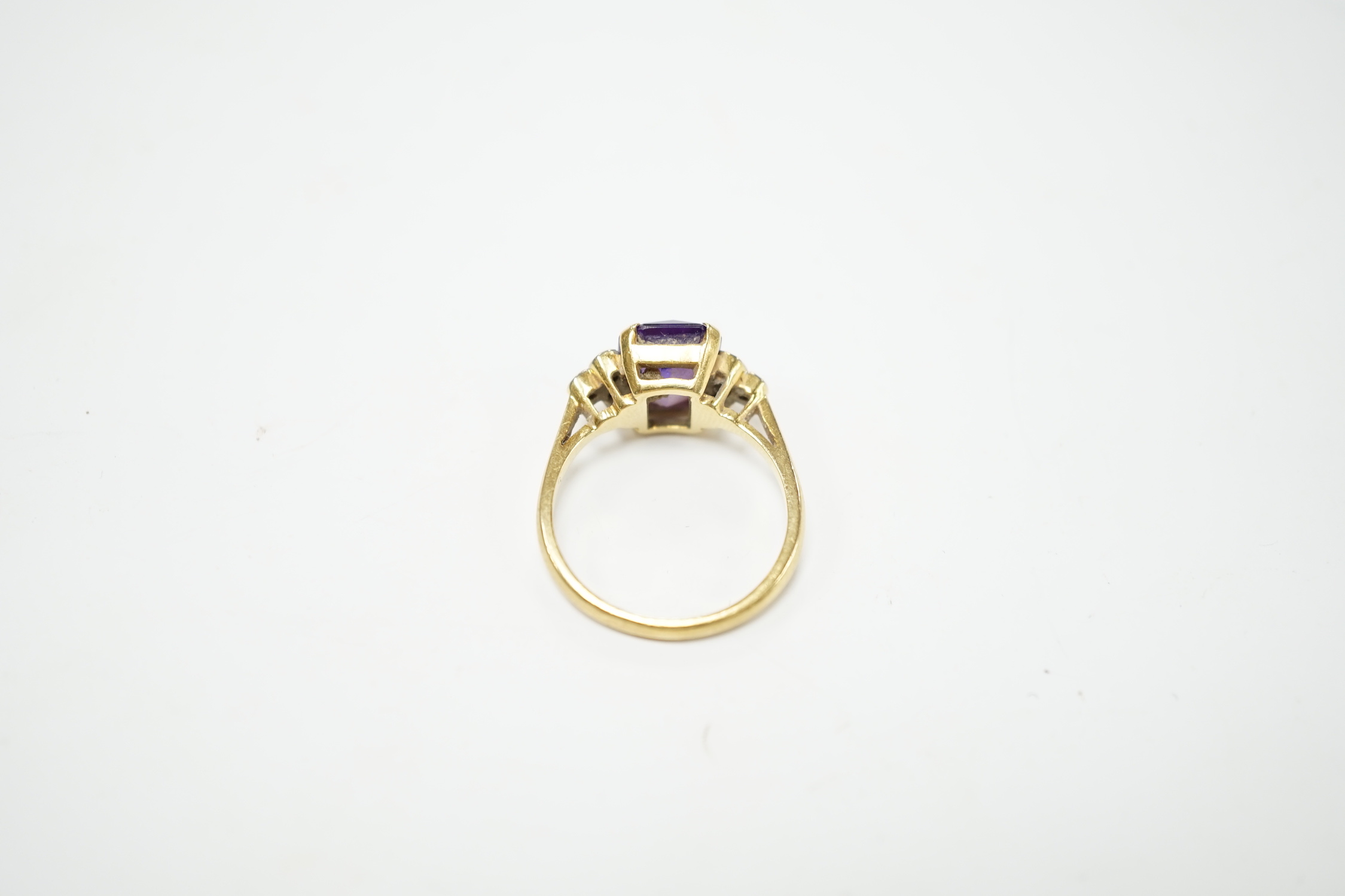 An 18ct and single stone emerald cut amethyst set ring with diamond set shoulders, size M, gross weight 4.5 grams.